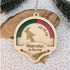 Bêtisomètre du Père Noël suspendu dans un sapin de Noël avec décorations et lumières.