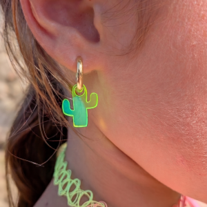 Fillette portant une créole dorée avec charm cactus en plexiglas vert néon translucide